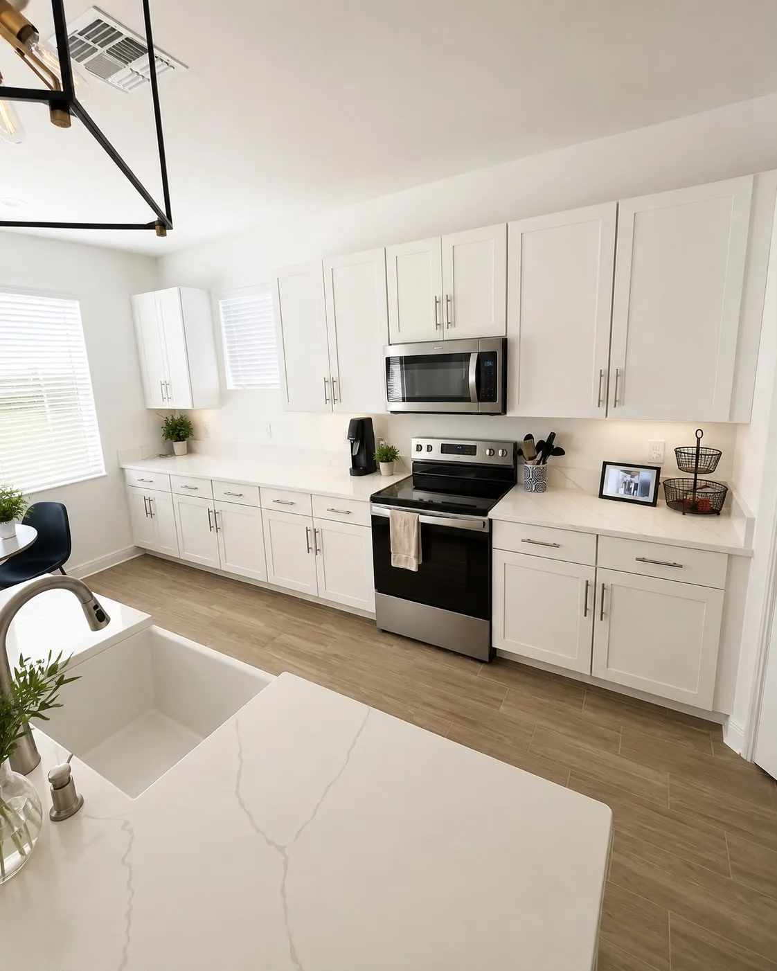 White shaker kitchen with quartz counters, a waterfall island and a farmhouse sink