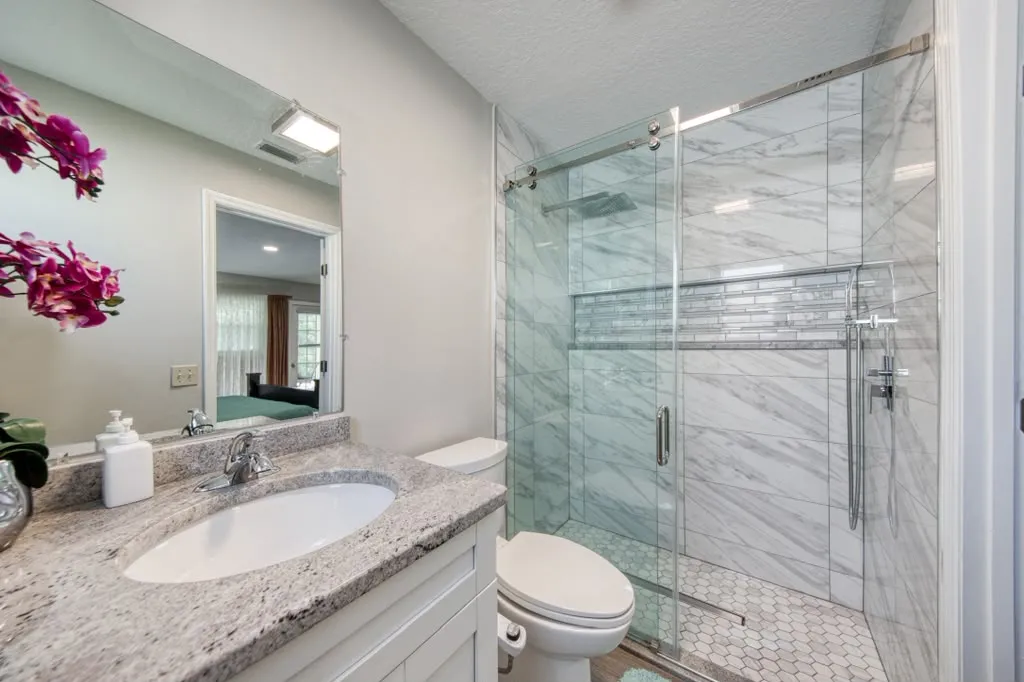 Walk-in shower in marble-look porcelain with a glass mosaic accent band