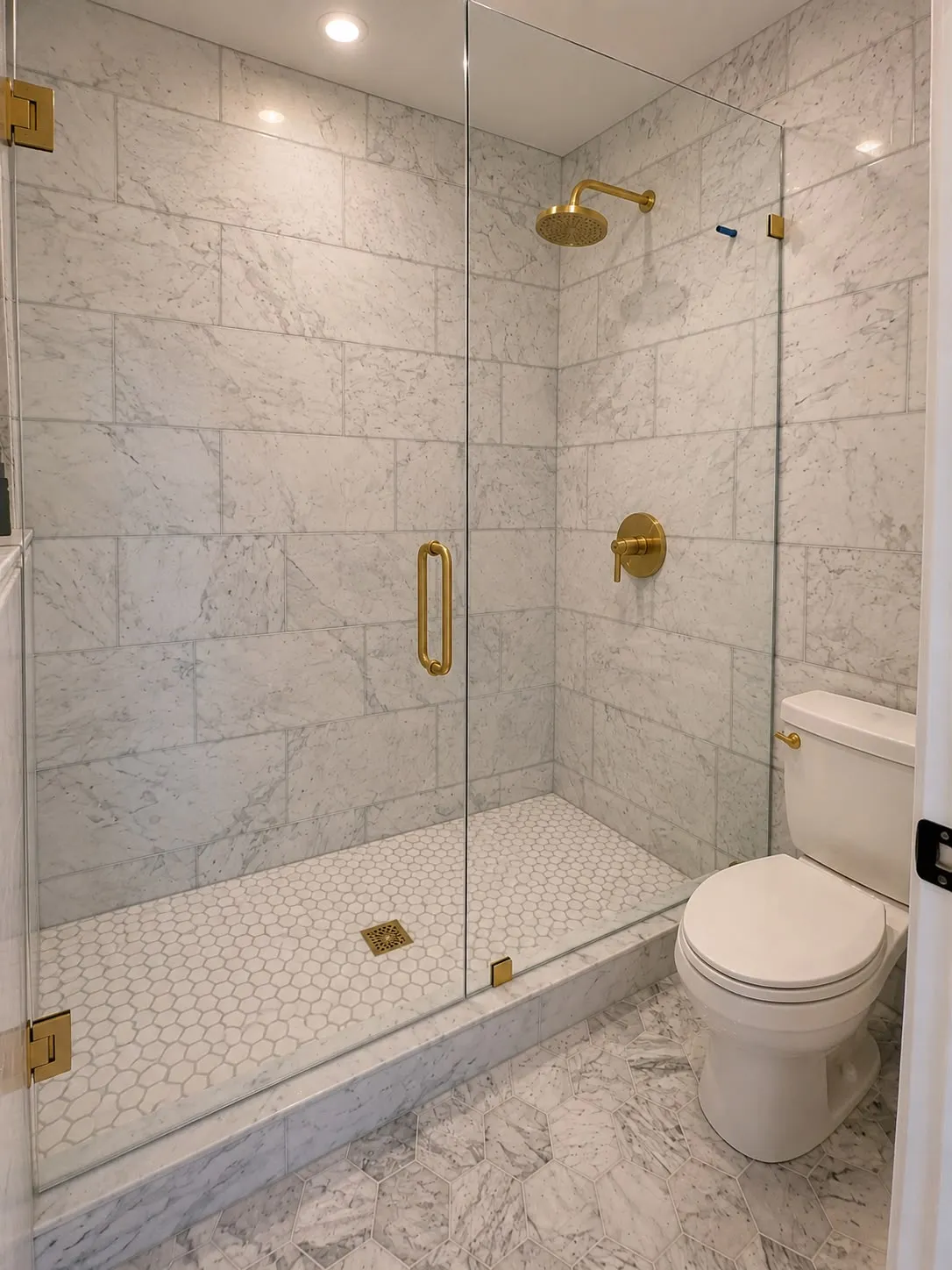 Marble shower with frameless glass, brass fittings and a hex mosaic pan