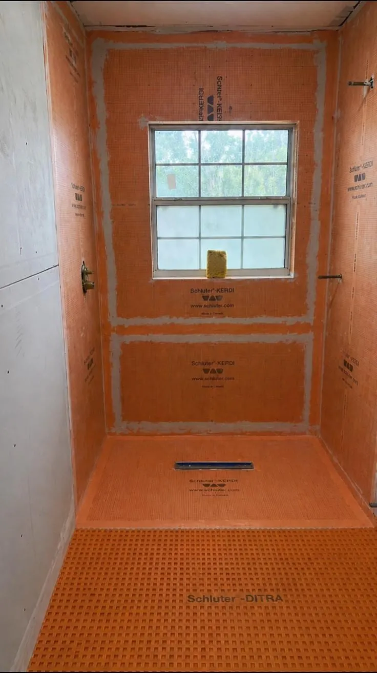 Shower walls and pre-sloped pan covered in bonded waterproofing membrane, linear drain set, before any tile