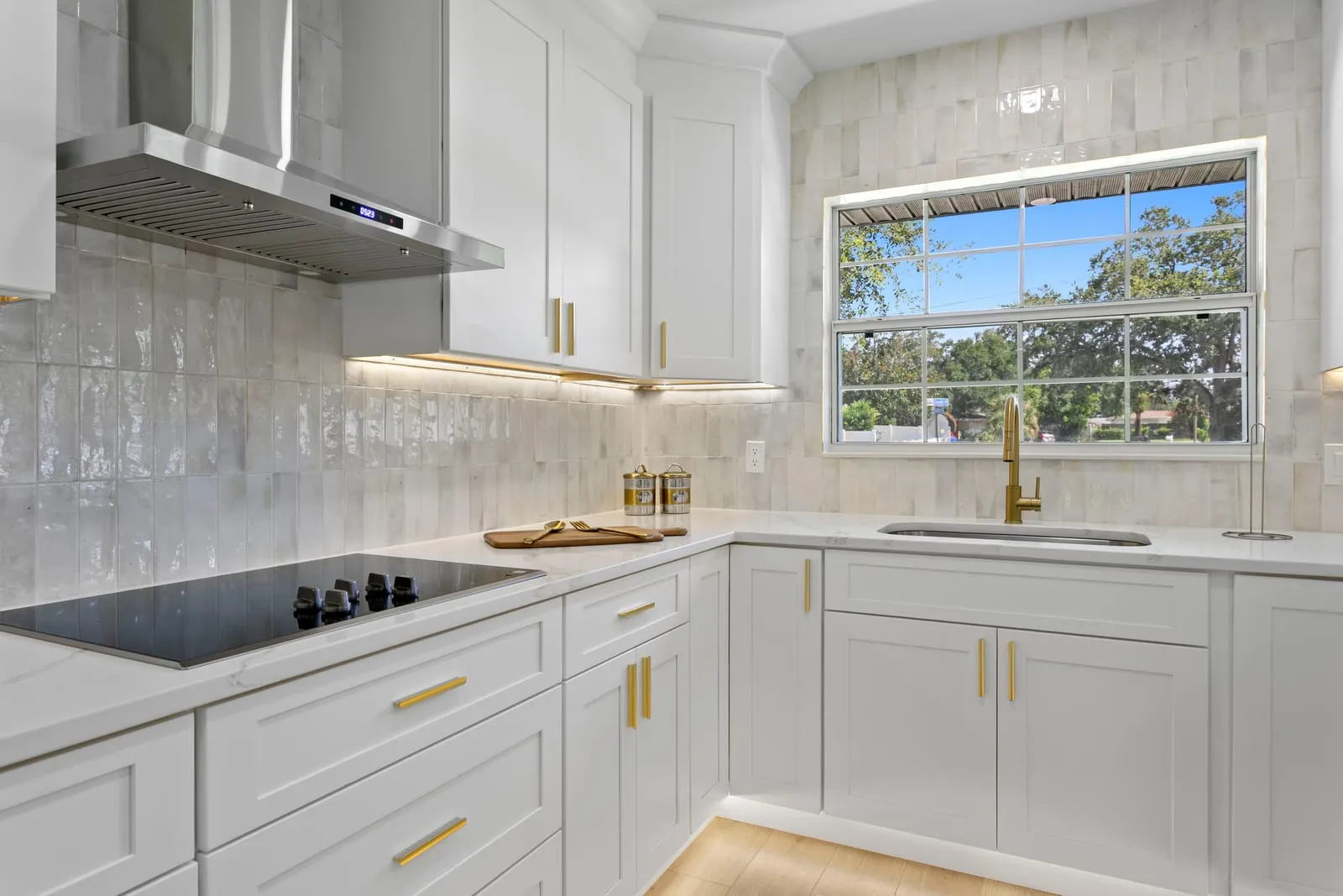 Rebuilt galley kitchen with quartz counters, a zellige backsplash and a stainless hood