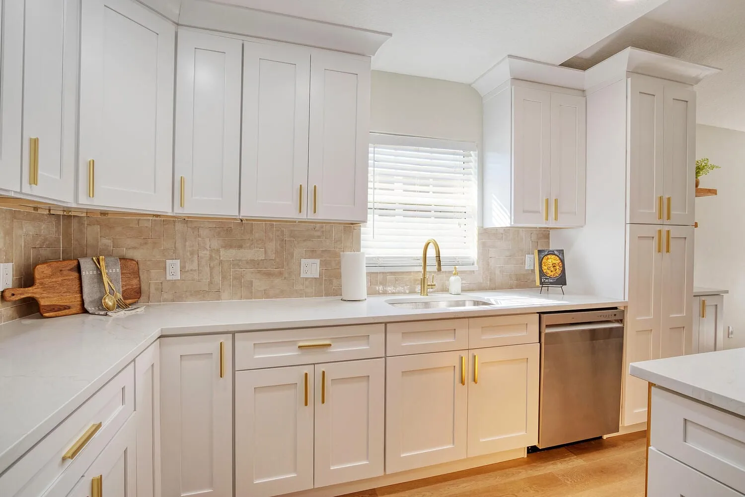 Renovated kitchen with a quartz island, vented hood and white shaker cabinetry