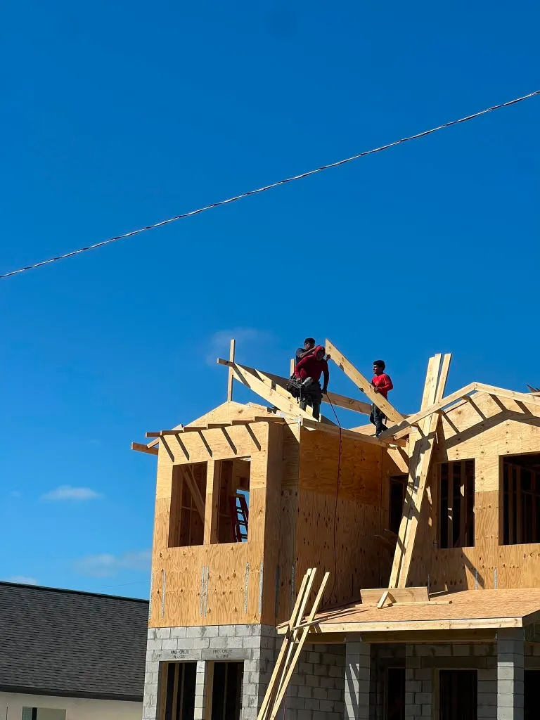 Framers setting engineered roof trusses on the second floor